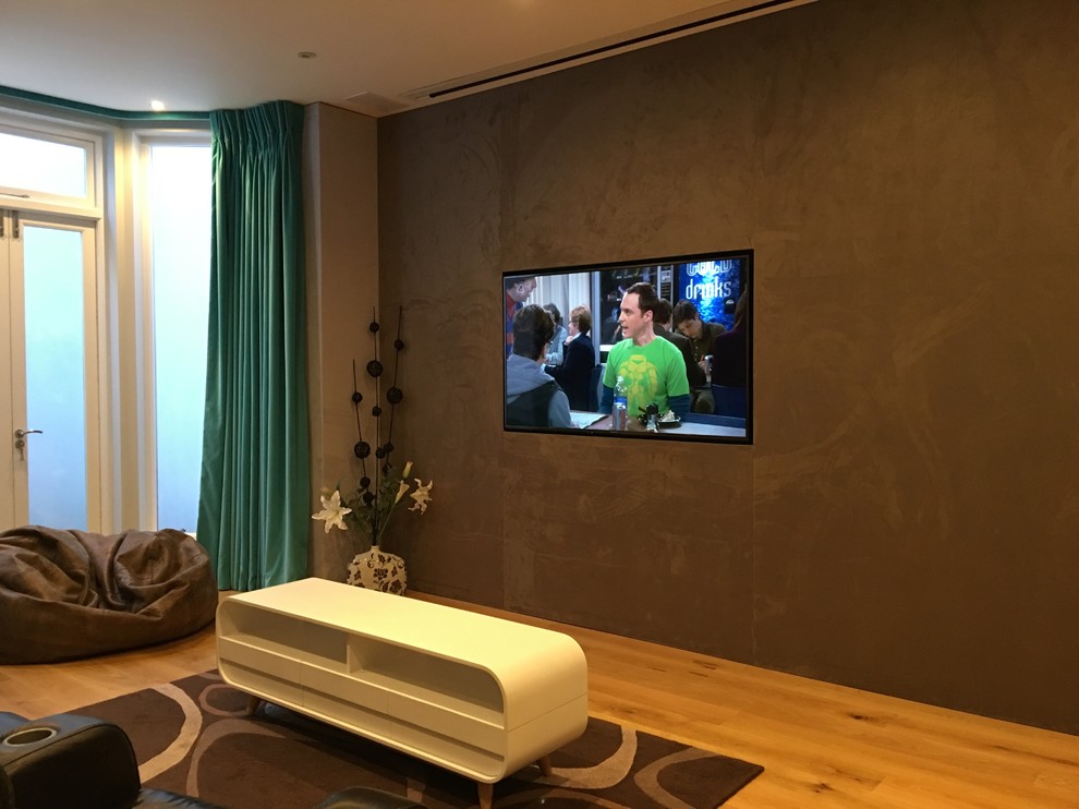 This is an example of a medium sized modern enclosed home cinema in London with brown walls and a projector screen.