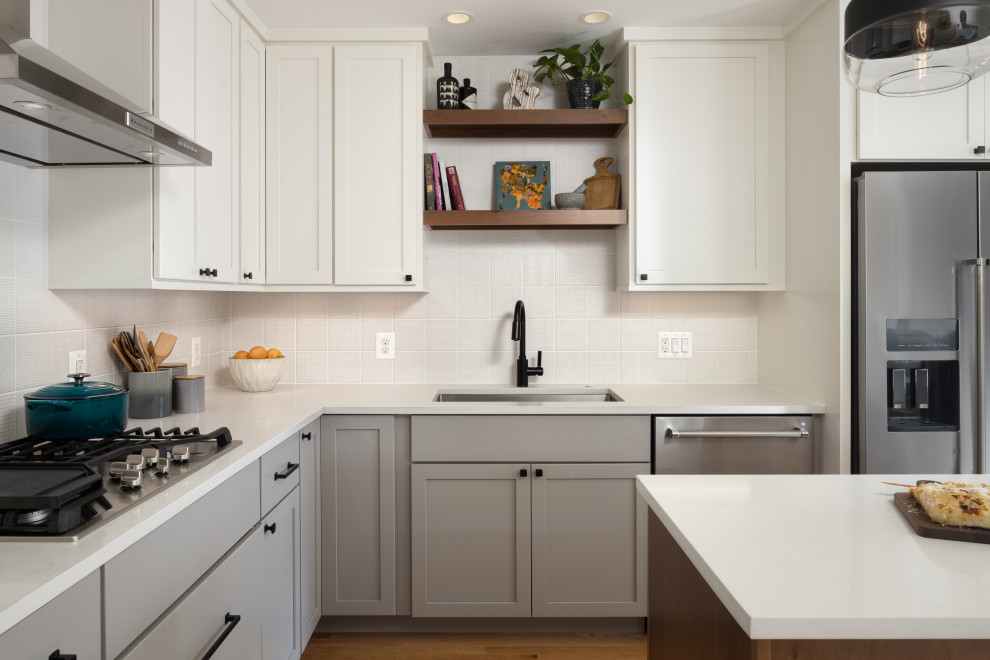 Design ideas for a mid-sized midcentury l-shaped eat-in kitchen in DC Metro with an undermount sink, shaker cabinets, white cabinets, quartz benchtops, white splashback, ceramic splashback, stainless steel appliances, medium hardwood floors, with island, brown floor and white benchtop.