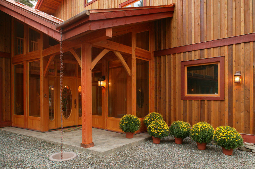 This is an example of a large country front door in Vancouver with brown walls, concrete floors, a single front door and a medium wood front door.
