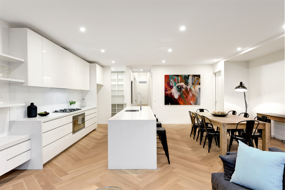 Inspiration for a contemporary galley eat-in kitchen in Melbourne with an undermount sink, flat-panel cabinets, white cabinets, medium hardwood floors and with island.