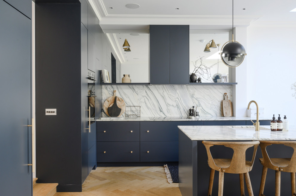 Large contemporary eat-in kitchen in London with an undermount sink, flat-panel cabinets, blue cabinets, marble benchtops, multi-coloured splashback, marble splashback, light hardwood floors, with island, brown floor and multi-coloured benchtop.