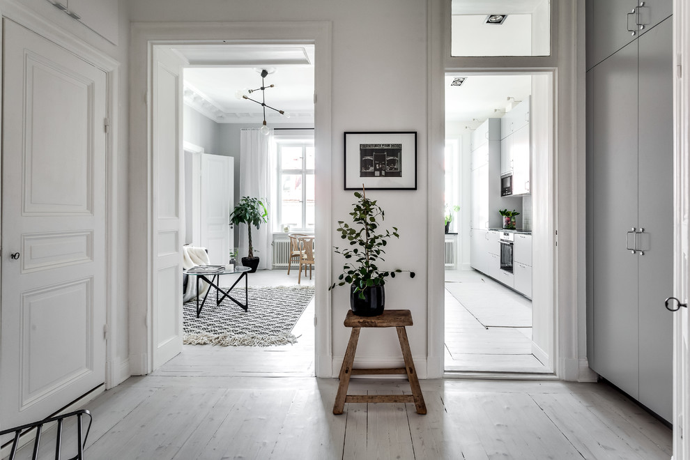 Photo of a mid-sized scandinavian hallway in Stockholm with white walls and painted wood floors.