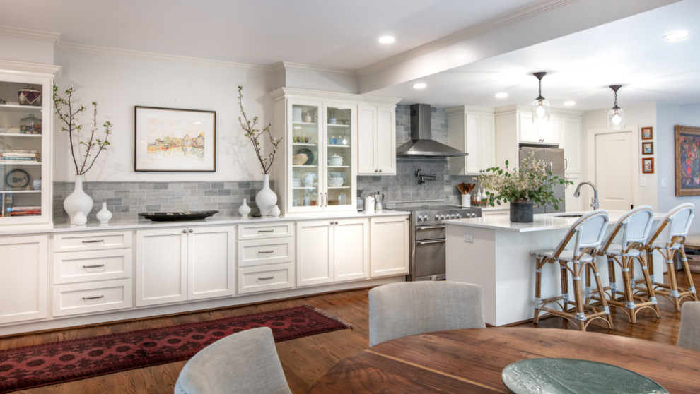 Inspiration for a mid-sized traditional single-wall eat-in kitchen in Houston with a drop-in sink, shaker cabinets, white cabinets, quartz benchtops, grey splashback, stone tile splashback, stainless steel appliances, medium hardwood floors, with island, multi-coloured floor and white benchtop.