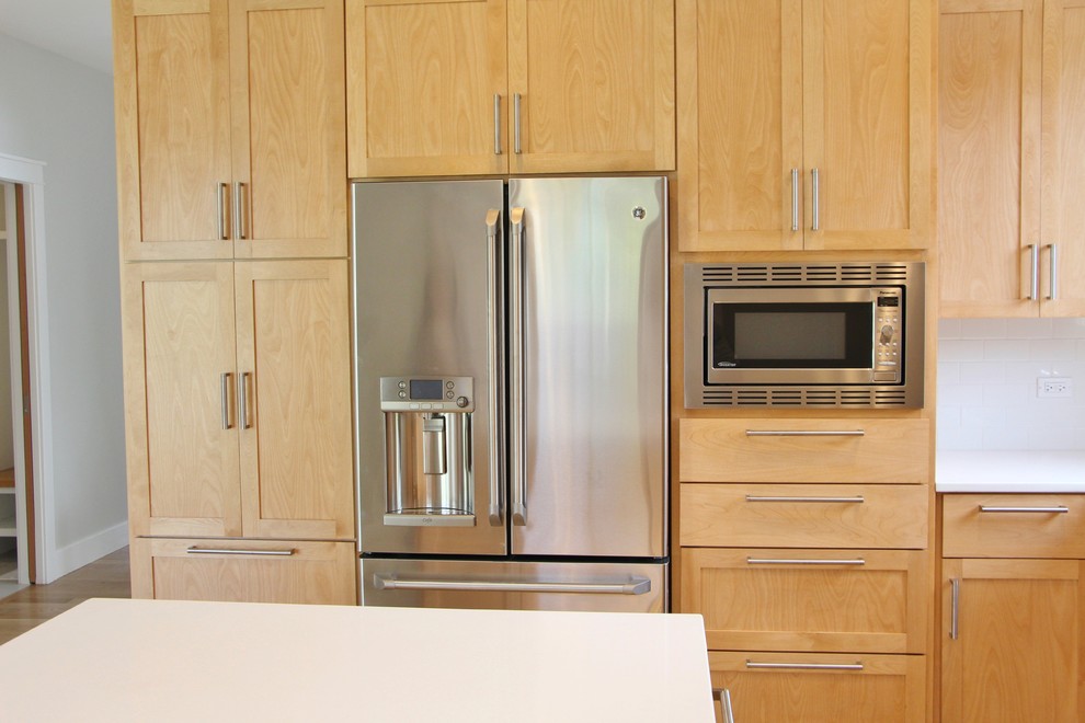 Mid-sized transitional l-shaped light wood floor eat-in kitchen photo in Chicago with an undermount sink, shaker cabinets, light wood cabinets, quartz countertops, white backsplash, subway tile backsplash, stainless steel appliances and an island