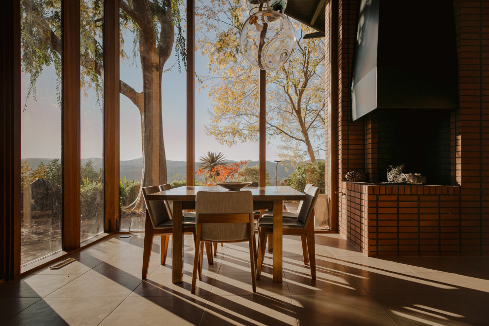 Inspiration pour une salle à manger minimaliste en bois fermée et de taille moyenne avec un mur marron, une cheminée d'angle, un manteau de cheminée en brique, un sol beige et un plafond en bois.
