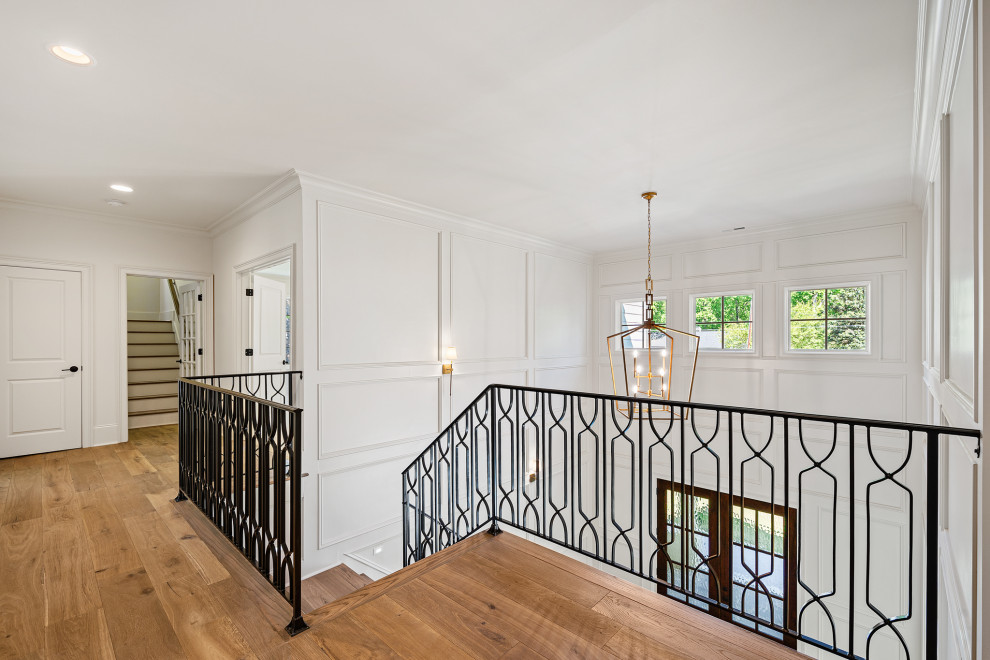 Large traditional wood l-shaped staircase in Raleigh with painted wood risers, metal railing and decorative wall panelling.