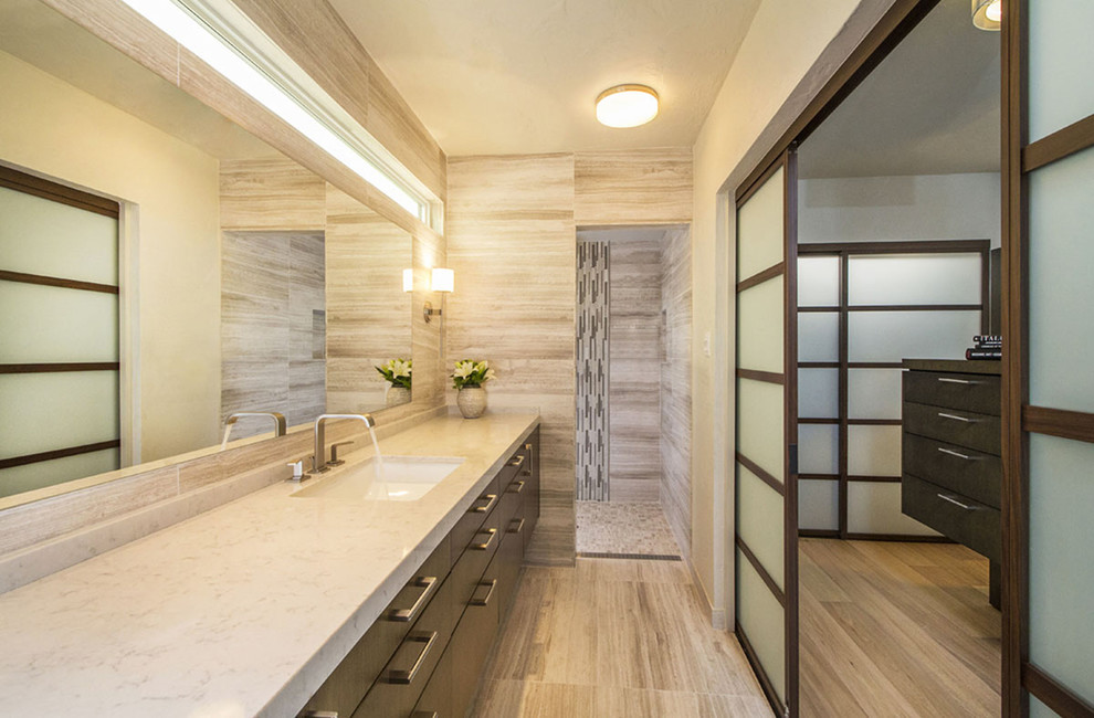 This is an example of a mid-sized contemporary master bathroom in San Diego with an undermount sink, a curbless shower, beige tile, flat-panel cabinets, medium wood cabinets, engineered quartz benchtops, stone tile, beige walls, limestone floors, beige floor and an open shower.
