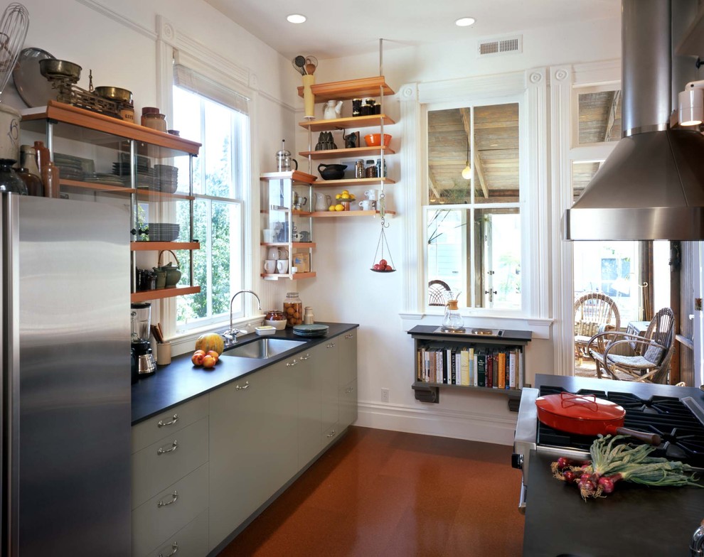 Photo of an industrial kitchen in San Francisco with stainless steel appliances, a single-bowl sink and open cabinets.