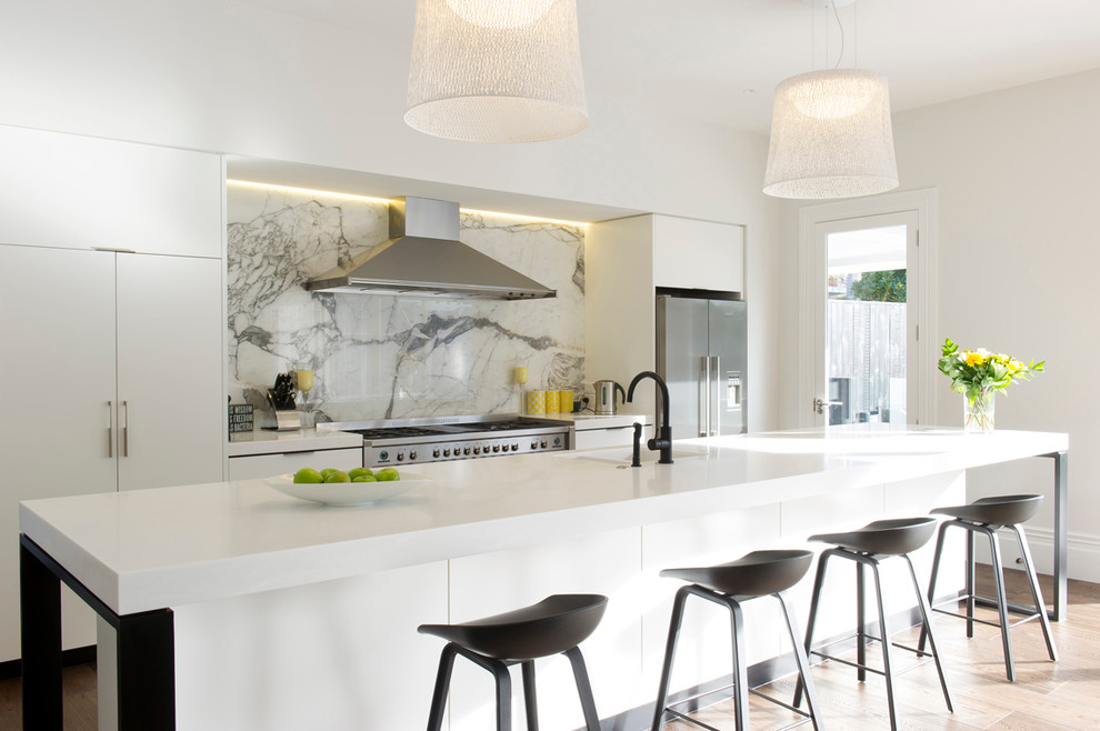 Photo of a large contemporary galley kitchen in Auckland with a double-bowl sink, flat-panel cabinets, white cabinets, grey splashback, stone slab splashback and with island.