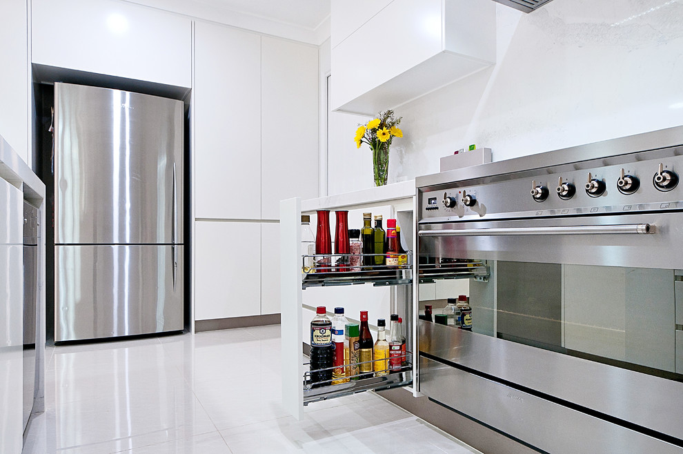 Design ideas for a large contemporary l-shaped open plan kitchen in Brisbane with an undermount sink, flat-panel cabinets, white cabinets, quartz benchtops, white splashback, stone slab splashback, stainless steel appliances, ceramic floors and with island.
