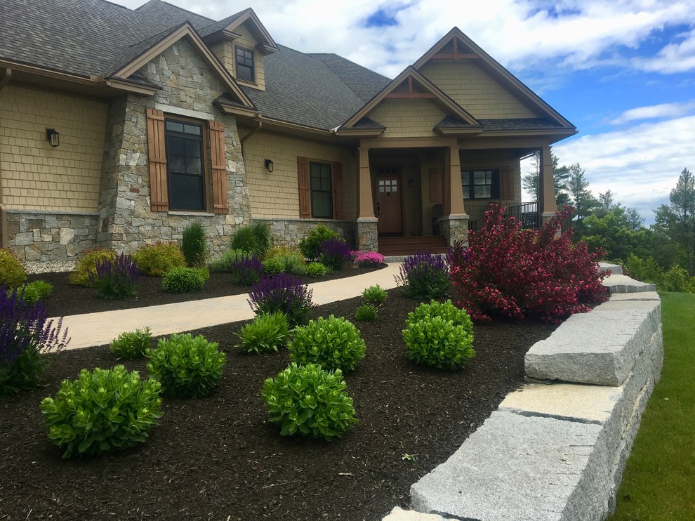 This is an example of a front yard garden in Other with a retaining wall and concrete pavers.