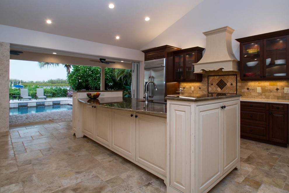 This is an example of a mediterranean open plan kitchen in Tampa with recessed-panel cabinets, granite benchtops and with island.
