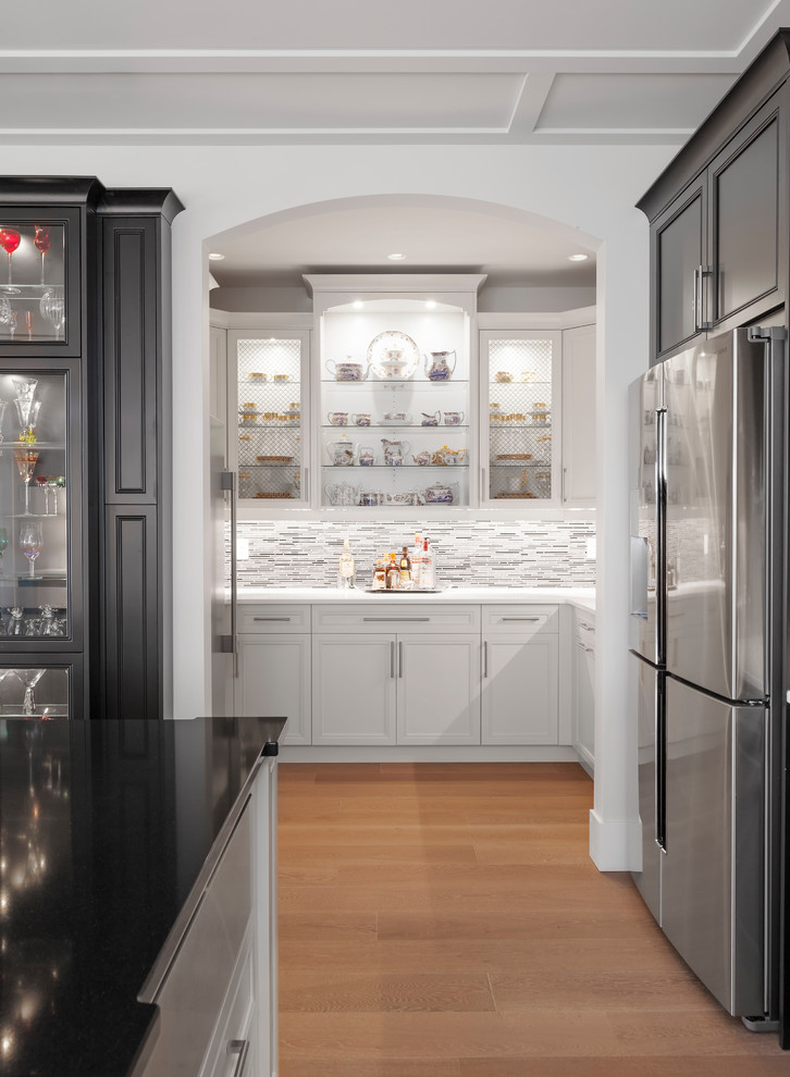 Kitchen pantry - large transitional u-shaped medium tone wood floor and brown floor kitchen pantry idea with an undermount sink, recessed-panel cabinets, quartz countertops, gray backsplash, glass tile backsplash, stainless steel appliances, an island, white countertops and white cabinets