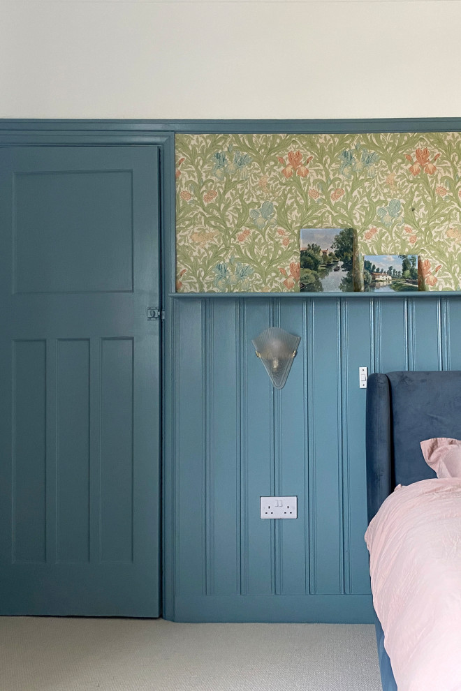Mittelgroßes Uriges Hauptschlafzimmer mit blauer Wandfarbe, Teppichboden, Kamin, Kaminumrandung aus Holzdielen, grauem Boden und Tapetenwänden in London