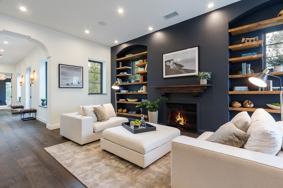 This is an example of a transitional open concept family room in Los Angeles with a library, dark hardwood floors, a standard fireplace and brown floor.