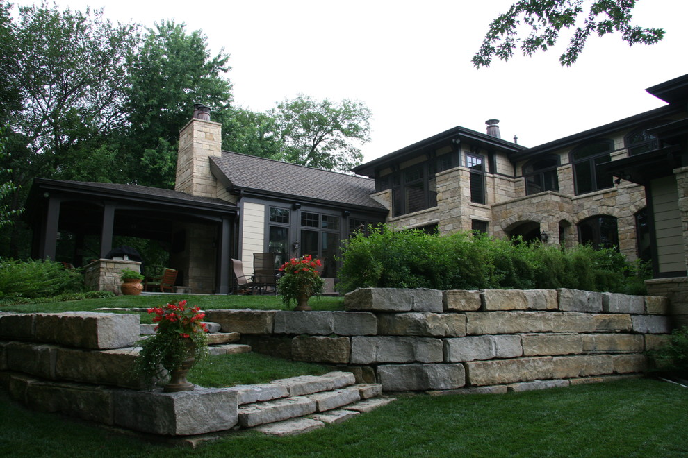 This is an example of a mid-sized traditional two-storey brown house exterior in Omaha with stone veneer, a gable roof and a shingle roof.