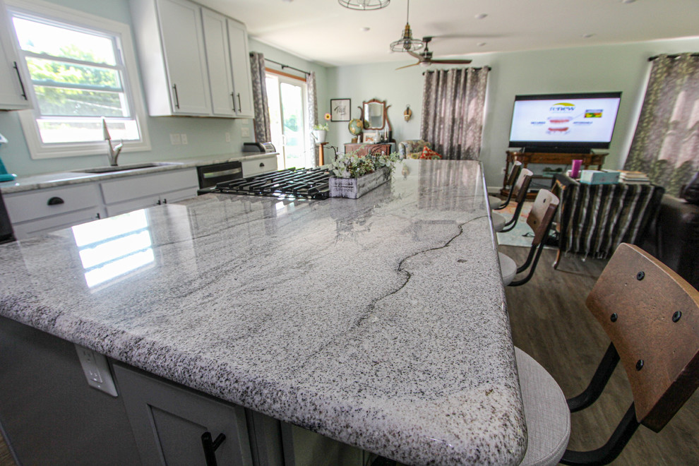 Mid-sized transitional single-wall laminate floor and brown floor open concept kitchen photo in Minneapolis with an undermount sink, shaker cabinets, gray cabinets, granite countertops, stainless steel appliances, an island and gray countertops
