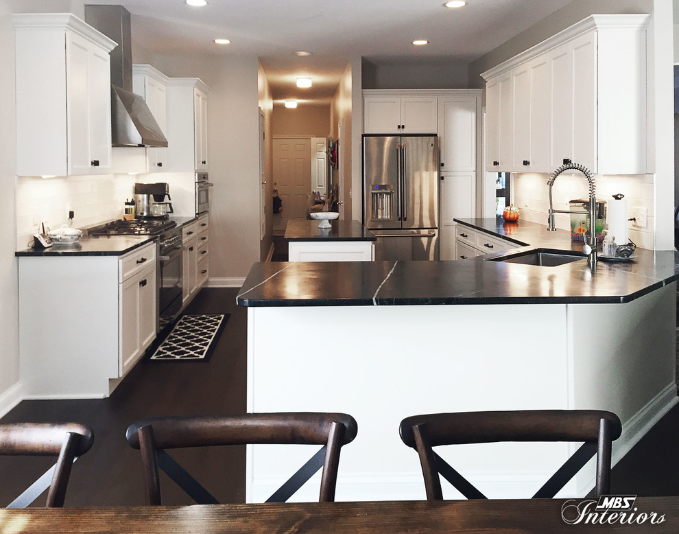 Eat-in kitchen - mid-sized transitional u-shaped dark wood floor and brown floor eat-in kitchen idea with an undermount sink, recessed-panel cabinets, white cabinets, soapstone countertops, white backsplash, subway tile backsplash, stainless steel appliances and an island