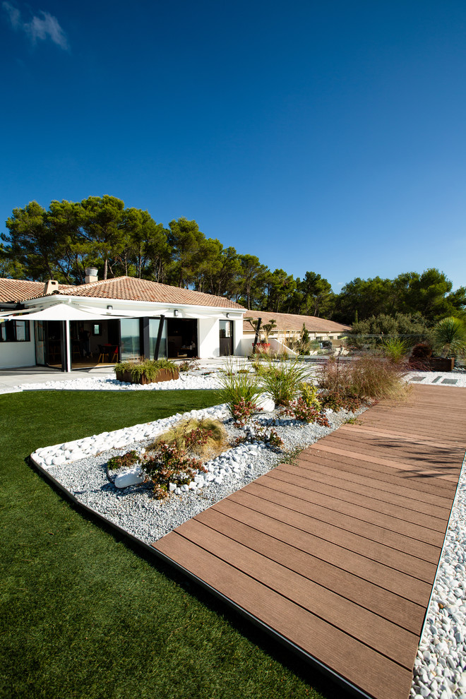 Photo of a large contemporary patio in Montpellier with gravel, an awning and a container garden.