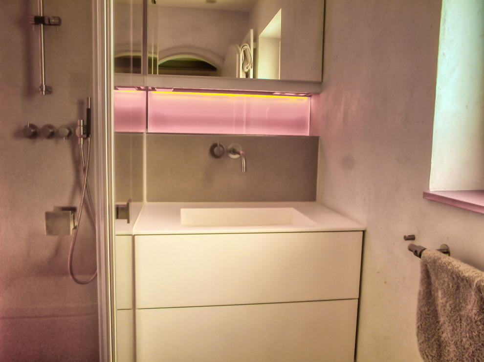 Photo of a small contemporary 3/4 bathroom in Munich with flat-panel cabinets, white cabinets, a curbless shower, a two-piece toilet, beige tile, ceramic tile, beige walls, ceramic floors, an integrated sink, solid surface benchtops, beige floor, a hinged shower door, white benchtops, a single vanity, a floating vanity and recessed.