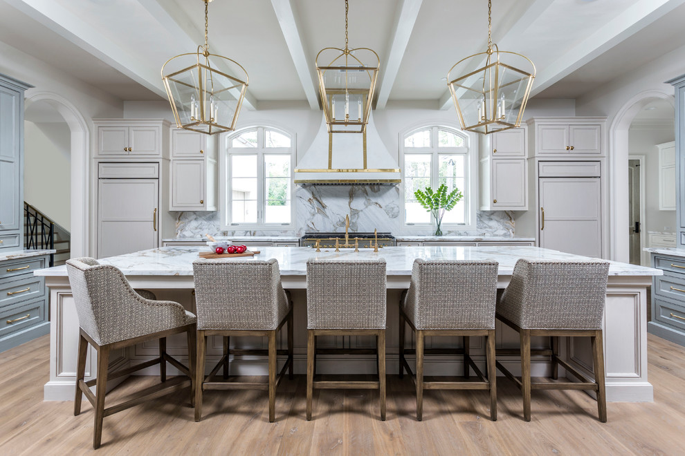 Photo of a transitional u-shaped kitchen in Houston with a farmhouse sink, beaded inset cabinets, grey cabinets, white splashback, panelled appliances, medium hardwood floors, with island, brown floor and white benchtop.