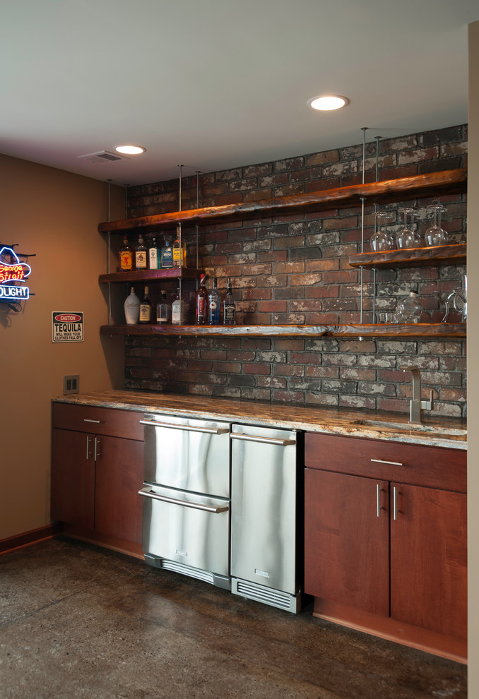 Mid-sized industrial single-wall wet bar in Wichita with an undermount sink, flat-panel cabinets, dark wood cabinets, granite benchtops, red splashback and brick splashback.