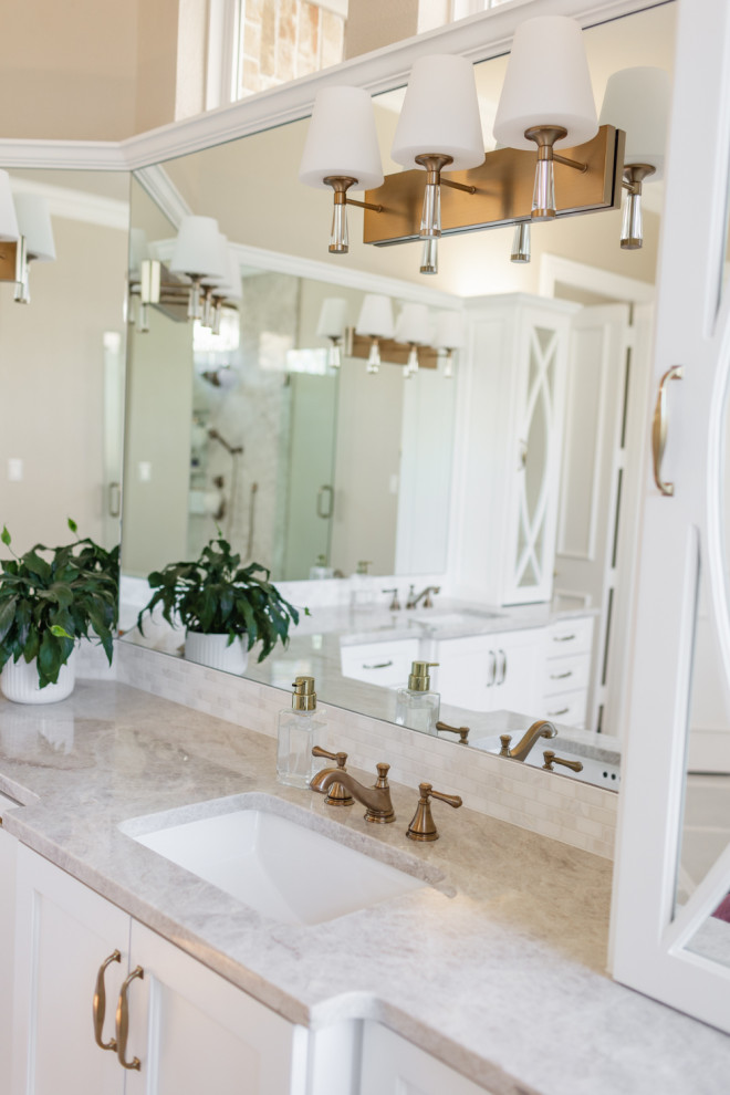 This is an example of a mid-sized transitional master bathroom in Dallas with recessed-panel cabinets, white cabinets, a freestanding tub, a corner shower, a one-piece toilet, beige tile, stone slab, beige walls, porcelain floors, an undermount sink, quartzite benchtops, beige floor, a hinged shower door, beige benchtops, an enclosed toilet, a double vanity and a built-in vanity.
