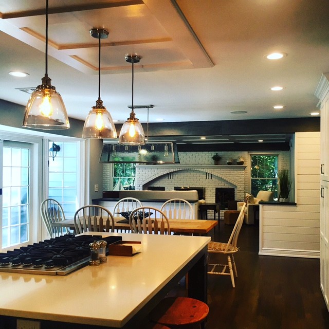 This is an example of a country eat-in kitchen in New York with a farmhouse sink, shaker cabinets, white cabinets, quartzite benchtops, white splashback, subway tile splashback, stainless steel appliances, dark hardwood floors and with island.