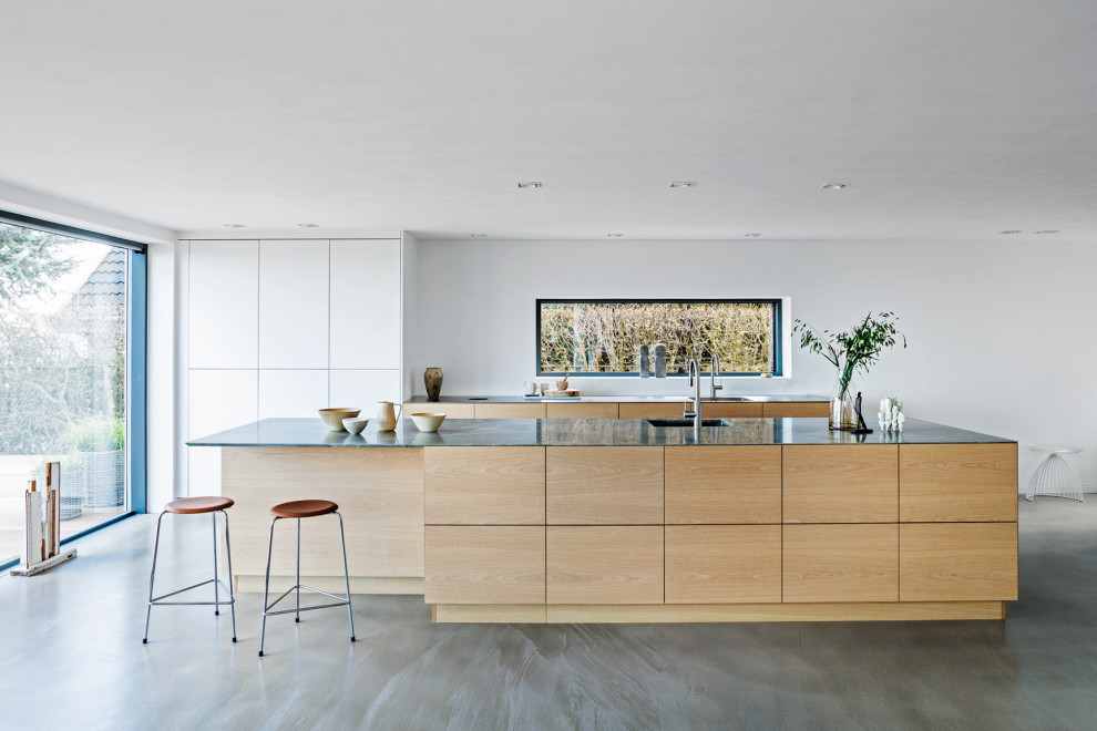 Idéer för att renovera ett mellanstort minimalistiskt grå grått kök, med en undermonterad diskho, släta luckor, bänkskiva i kvartsit, betonggolv, en köksö och grått golv