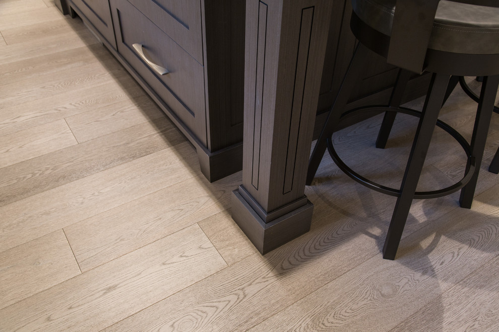 Inspiration for a large transitional l-shaped medium tone wood floor and beige floor eat-in kitchen remodel in Vancouver with an undermount sink, shaker cabinets, white cabinets, granite countertops, gray backsplash, marble backsplash, stainless steel appliances, an island and black countertops