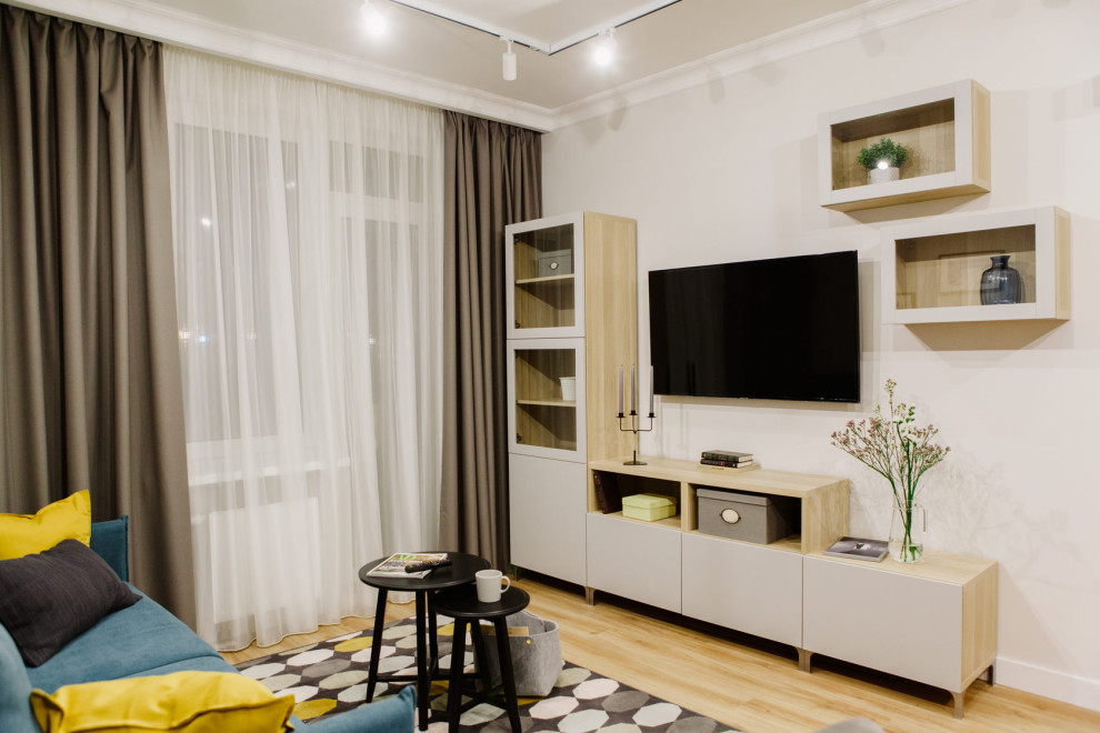 На фото: гостиная комната в современном стиле с бежевыми стенами, полом из керамической плитки, телевизором на стене, желтым полом, обоями на стенах и синим диваном с