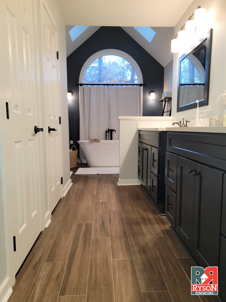 Example of a trendy master white tile and ceramic tile laminate floor, brown floor, double-sink and vaulted ceiling bathroom design in Richmond with recessed-panel cabinets, black cabinets, gray walls, an undermount sink, white countertops and a freestanding vanity