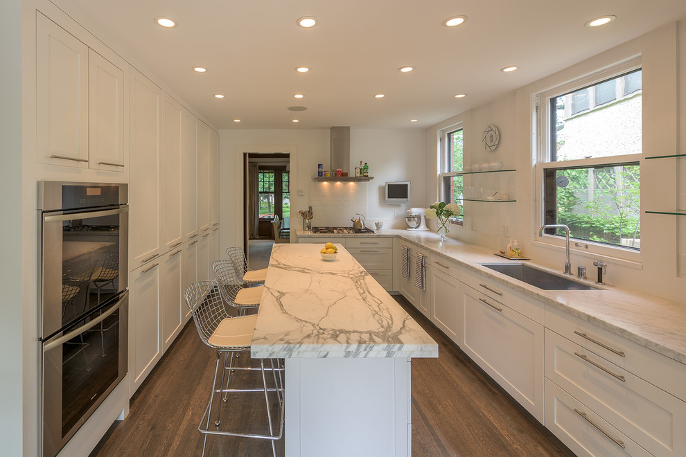 Inspiration for a large transitional u-shaped separate kitchen in Minneapolis with an undermount sink, shaker cabinets, white cabinets, marble benchtops, white splashback, porcelain splashback, stainless steel appliances, dark hardwood floors and with island.
