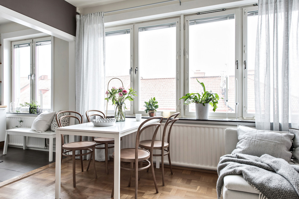 Small scandinavian dining room in Gothenburg with brown walls, medium hardwood floors and beige floor.