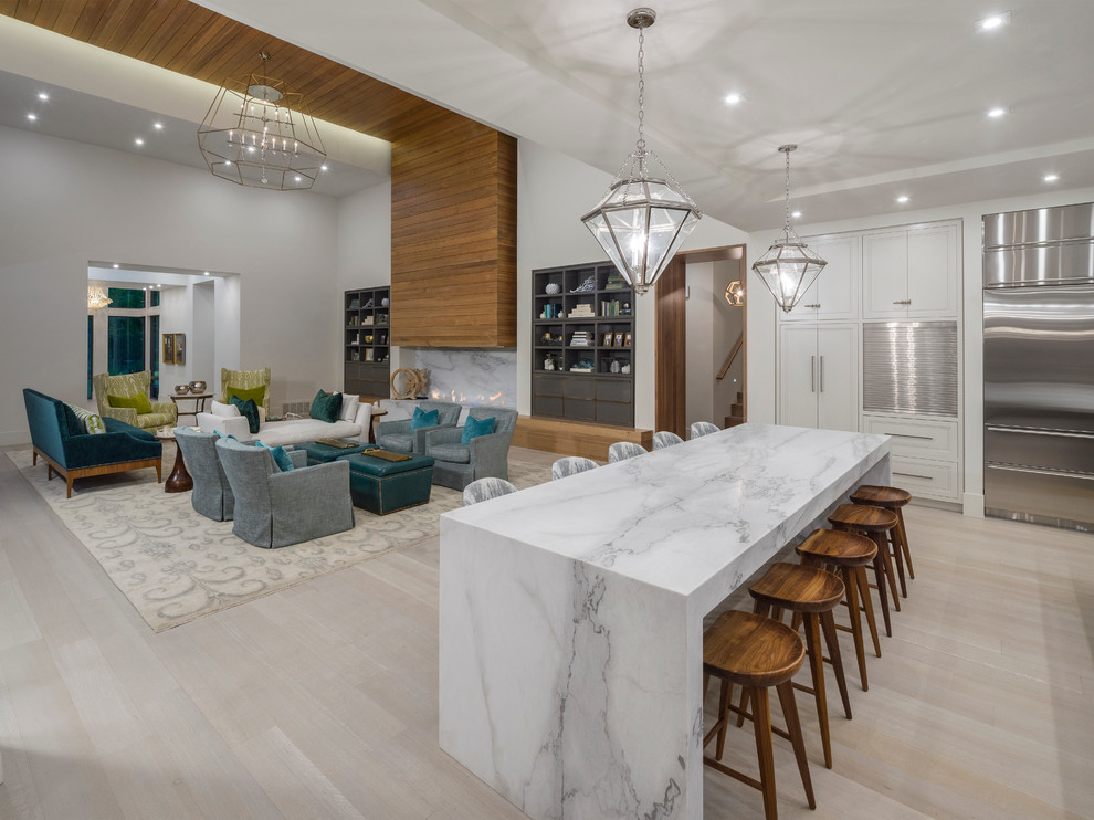 This is an example of a large contemporary galley open plan kitchen in Salt Lake City with recessed-panel cabinets, white cabinets, marble benchtops, white splashback, stone slab splashback, stainless steel appliances, light hardwood floors and multiple islands.