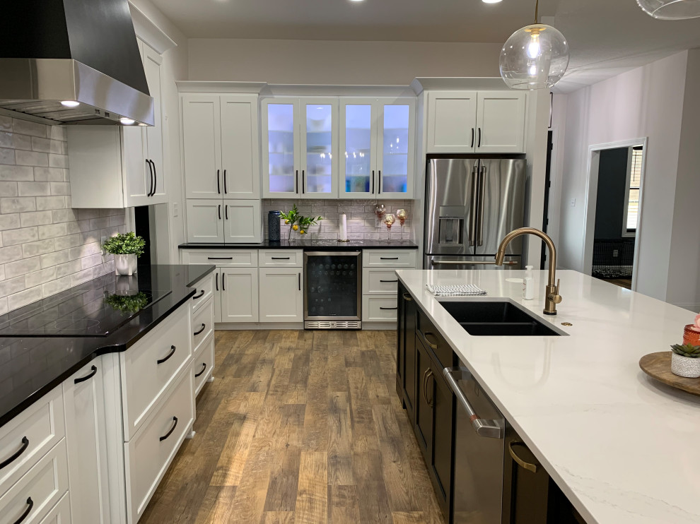 Inspiration for a large transitional l-shaped vinyl floor and brown floor open concept kitchen remodel with an undermount sink, recessed-panel cabinets, white cabinets, quartz countertops, white backsplash, ceramic backsplash, stainless steel appliances, an island and white countertops