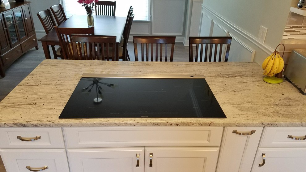 Eat-in kitchen - mid-sized transitional u-shaped medium tone wood floor and brown floor eat-in kitchen idea in Philadelphia with an undermount sink, recessed-panel cabinets, white cabinets, granite countertops, gray backsplash, glass tile backsplash, stainless steel appliances and a peninsula
