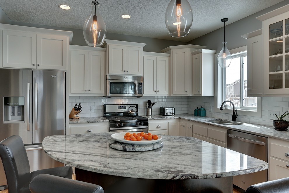 Inspiration for a transitional u-shaped open plan kitchen in Minneapolis with an undermount sink, shaker cabinets, white cabinets, granite benchtops, white splashback, subway tile splashback, stainless steel appliances, light hardwood floors and with island.