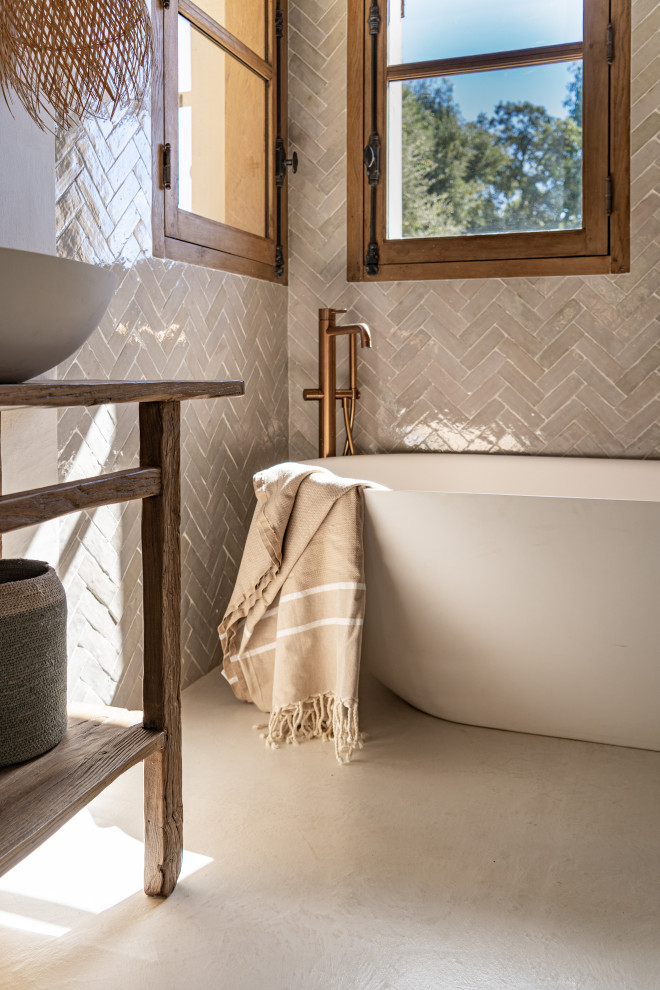 Cette image montre une grande salle de bain principale méditerranéenne avec une baignoire posée, un mur blanc, sol en béton ciré, un plan de toilette en bois, un sol beige et meuble simple vasque.