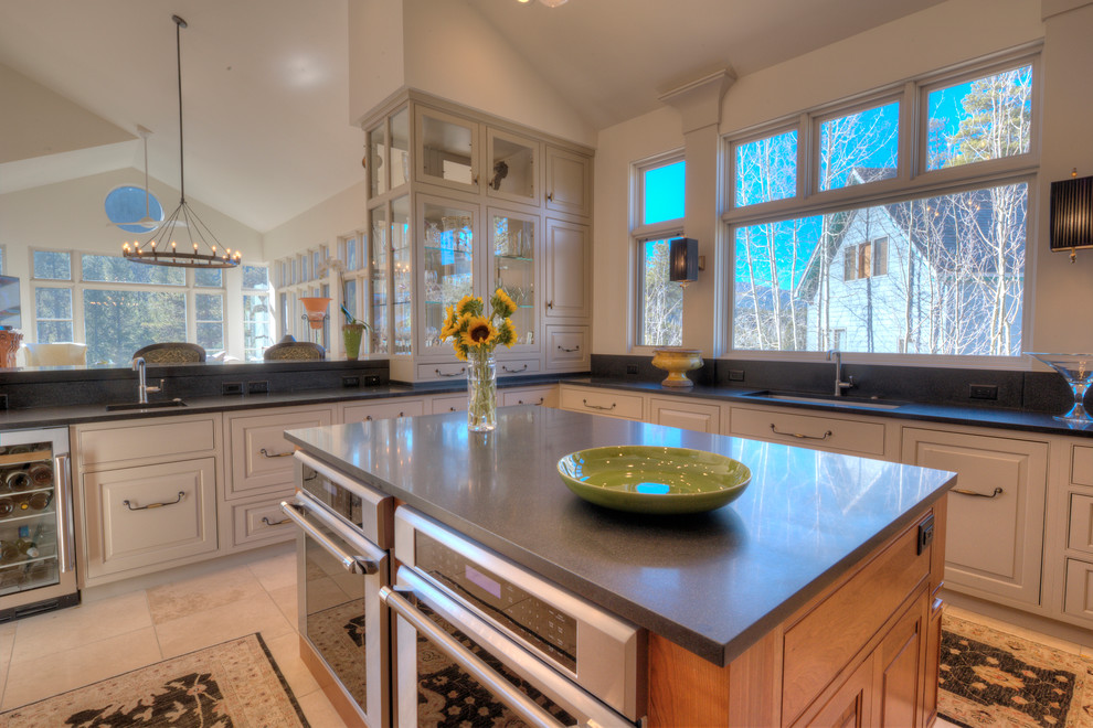 Enclosed kitchen - mid-sized rustic u-shaped travertine floor enclosed kitchen idea in Denver with an undermount sink, beaded inset cabinets, light wood cabinets, quartz countertops, beige backsplash, stone slab backsplash, paneled appliances and an island