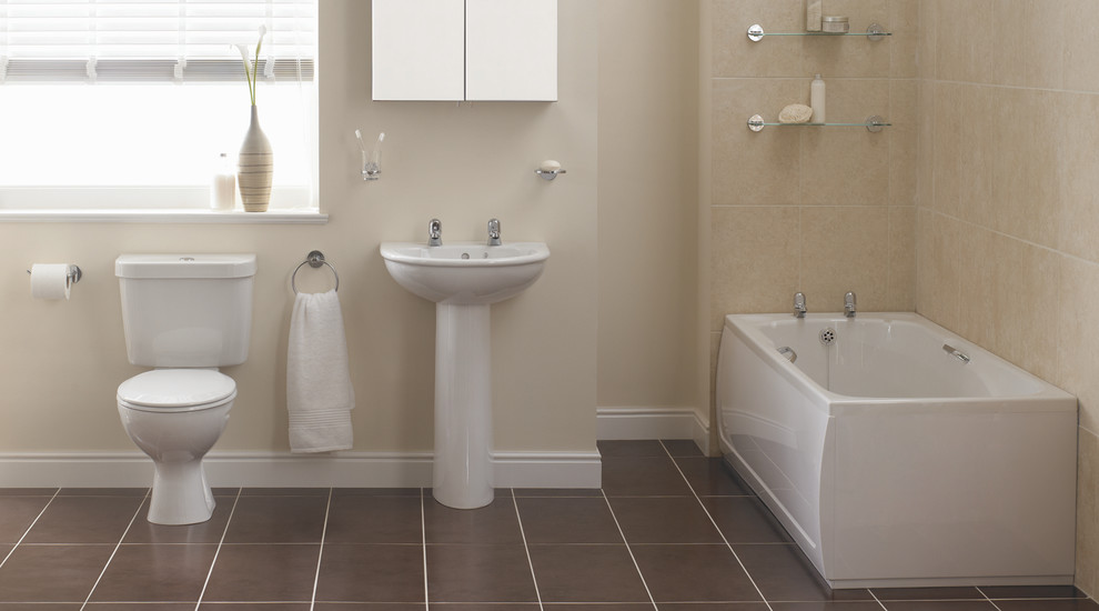 This is an example of a mid-sized contemporary bathroom in Hampshire with a wall-mount sink, a drop-in tub, a one-piece toilet, beige tile, beige walls and linoleum floors.