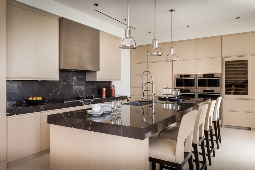 Photo of a contemporary kitchen in Miami with an undermount sink, flat-panel cabinets, light wood cabinets, black splashback, stainless steel appliances and with island.