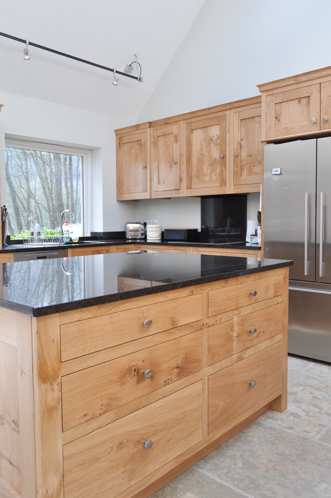 Photo of a large traditional l-shaped eat-in kitchen in Other with an undermount sink, shaker cabinets, light wood cabinets, granite benchtops, black splashback, stone slab splashback, stainless steel appliances, limestone floors and with island.