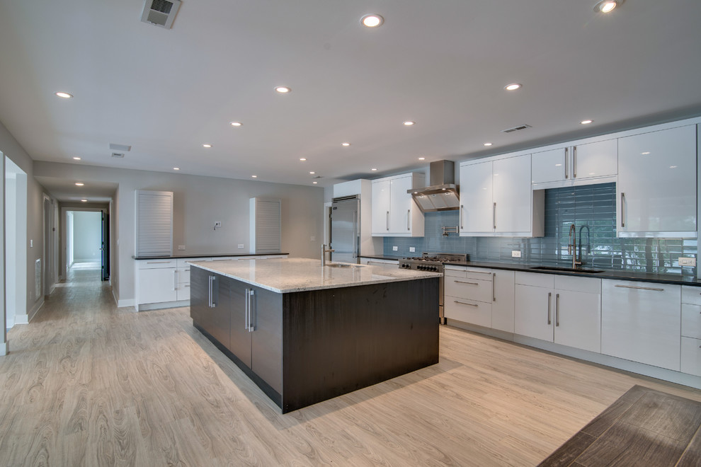 This is an example of a mid-sized beach style single-wall kitchen in Nashville with an undermount sink, flat-panel cabinets, white cabinets, quartzite benchtops, blue splashback, glass tile splashback, stainless steel appliances, linoleum floors and with island.