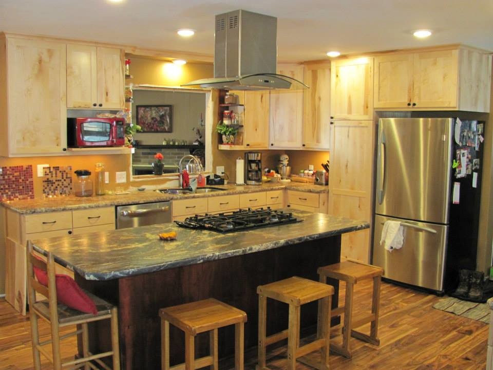 Example of a mid-sized mountain style l-shaped medium tone wood floor and brown floor eat-in kitchen design with a double-bowl sink, shaker cabinets, light wood cabinets, limestone countertops, stainless steel appliances and an island