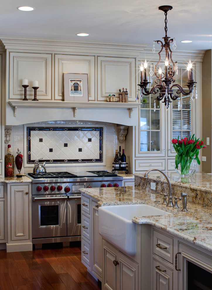 This is an example of a traditional kitchen in Chicago with a farmhouse sink, raised-panel cabinets, beige cabinets, beige splashback and stainless steel appliances.