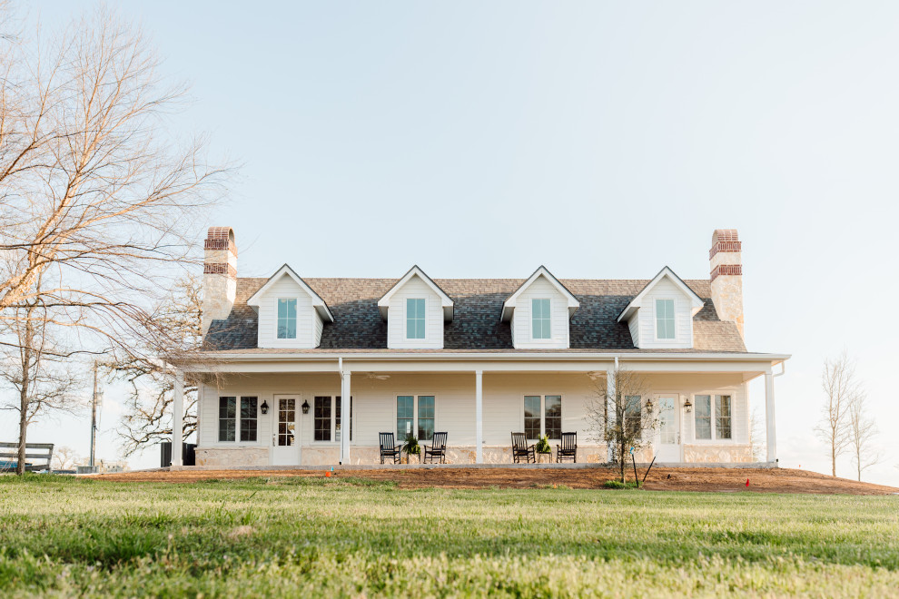 Mid-sized farmhouse beige one-story stone house exterior idea in Austin with a shingle roof and a brown roof