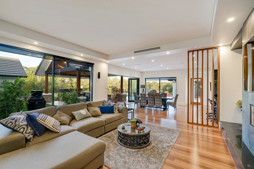 This is an example of a large tropical open concept living room in Sydney.