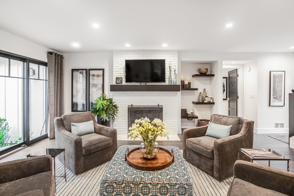 This is an example of a contemporary open concept family room in Grand Rapids with white walls, medium hardwood floors, a wood stove, a brick fireplace surround, a wall-mounted tv and brown floor.