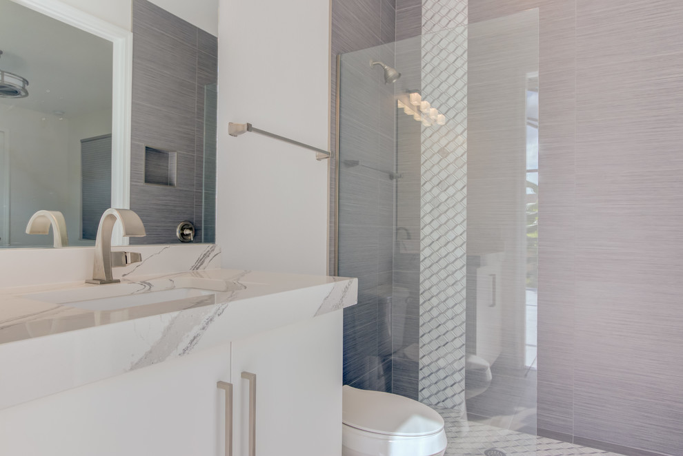 Small modern 3/4 bathroom in Other with flat-panel cabinets, white cabinets, an open shower, gray tile, ceramic tile, grey walls, ceramic floors, an undermount sink, engineered quartz benchtops, grey floor, an open shower and white benchtops.